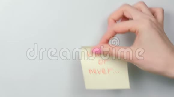 特写的女人她的手贴着黄色的贴纸纸上面写着现在或永远的话视频的预览图
