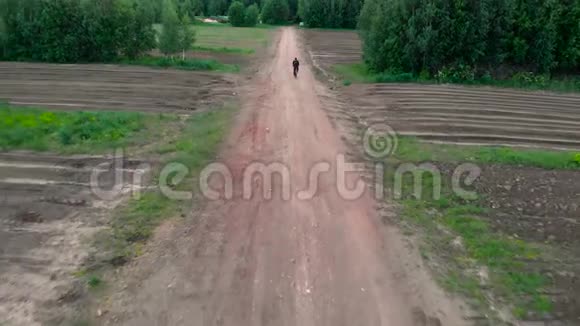 拍摄于日落时分镜头跟随男子骑自行车在土路上骑行视频的预览图
