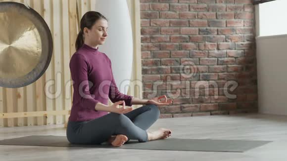 活泼的美女坐在画室的地板上坐着莲花姿势冥想视频的预览图