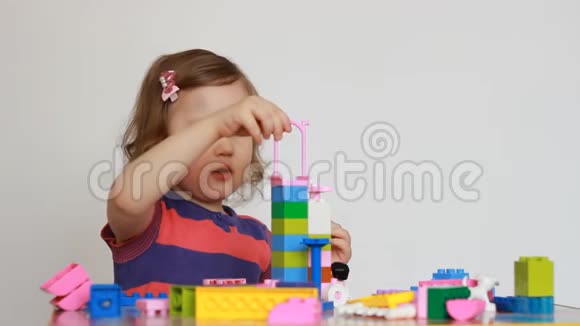 小女孩玩五颜六色的小积木的一个建设者孩子培养自己的思维能力发展视频的预览图