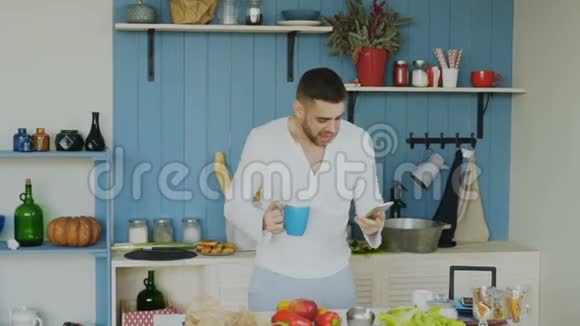 在智能手机上浏览社交媒体时帅哥在厨房里跳舞唱歌视频的预览图