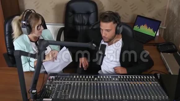漂亮的电台主持人头戴耳机的男女在录音棚里对着麦克风讲话视频的预览图