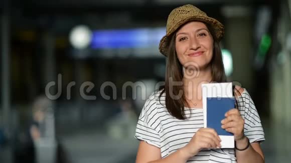 手里拿着机票和护照的兴奋的年轻女子正在机场等待一架飞机模糊记分板视频的预览图