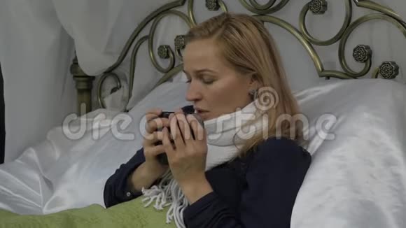 生病的女人躺在家里的床上喝着蜂蜜热饮料慢动作视频的预览图