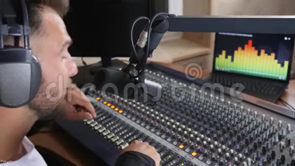 在录音室里用耳机对着麦克风讲话调整音量视频的预览图
