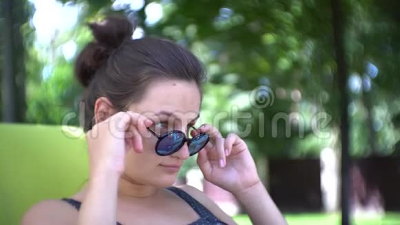 戴太阳镜的年轻女人在夏天的阳光下放松视频的预览图