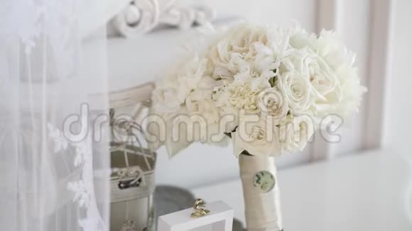 两个金色的结婚戒指放在一个白色的木箱里里面有玫瑰花和新娘花束视频的预览图