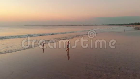 日落时分一名妇女和她的儿子在海边散步视频的预览图