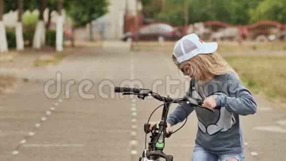 夏天一个金发女孩骑自行车在自行车道上视频的预览图