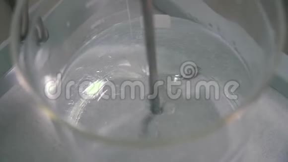 将粘稠液体在玻璃杯中与药物搅拌机混合的过程视频的预览图