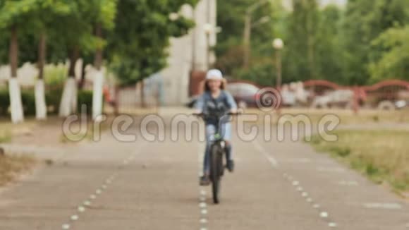 夏天一个金发女孩骑自行车在自行车道上视频的预览图