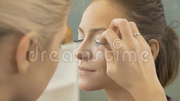 专业化妆师涂抹人造睫毛的模型艺术摄影的准备特写视频的预览图