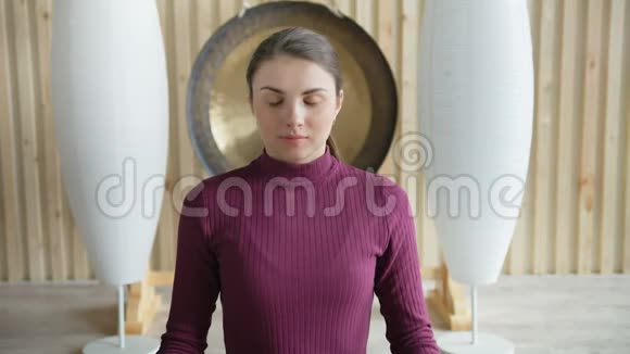 活泼的美女坐在画室的地板上坐着莲花姿势冥想视频的预览图