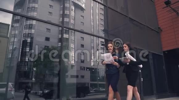 自信的商务女性走在现代商务中心的背景下一个拿着蓝图说话的女孩视频的预览图