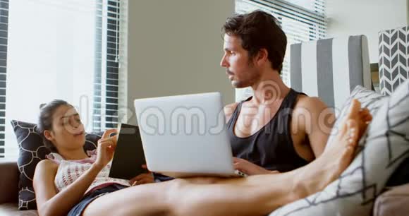 男人用笔记本电脑女人在客厅4k看书视频的预览图