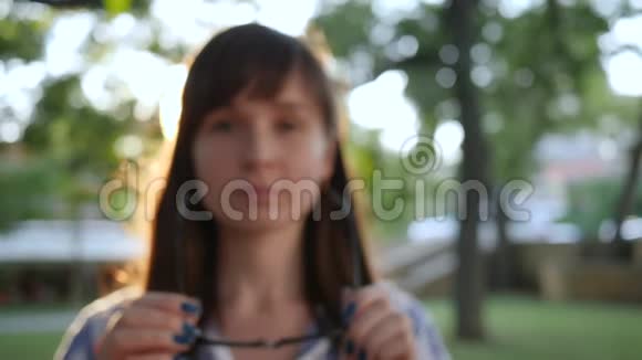 快乐的女性戴上时尚的眼镜在公园的摄像机上微笑特写镜头视频的预览图