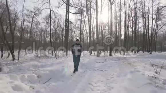 肖像运动员男子跑在冬季森林近距离城市公园冬季慢跑视频的预览图