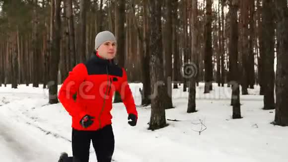 一个年轻的运动员冬天在森林里跑步视频的预览图