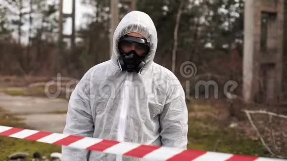 穿着生物危险服和防毒面具的人走到满是废物的土地上的高跷前视频的预览图