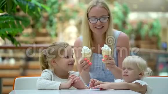 小女孩在大购物中心吃冰淇淋和一个喇叭家人在商场里吃冰淇淋家庭幸福可爱视频的预览图
