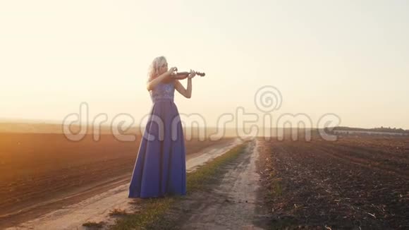 一位年轻女子在阳光下的剪影吹着小提琴女孩沿着音乐的琴弦放松和移动视频的预览图