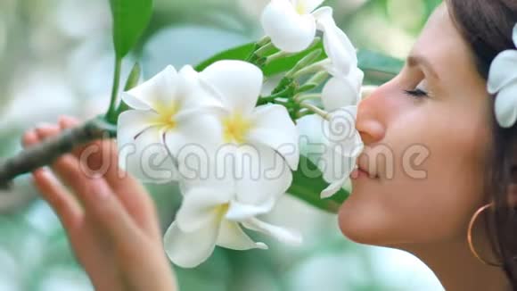 美丽的年轻女子留着长发在花园里摆着春天的花朵视频的预览图