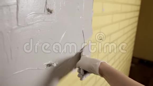 戴白色手套的女孩在修理前放了一堵墙蜘蛛网石膏光滑的墙壁视频的预览图