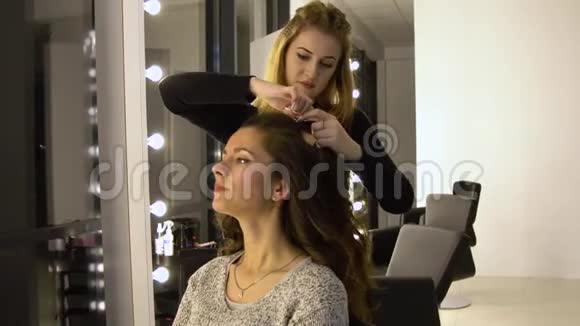 美容院的年轻漂亮女孩理发师发型师使女孩头发理发师用一个视频的预览图