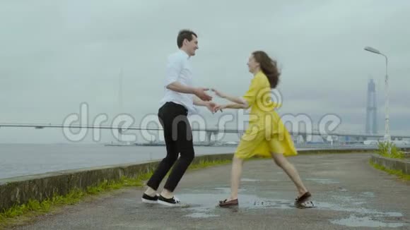 雨后快乐的男人和女人在水坑上跳舞穿黄色衣服的女孩视频的预览图