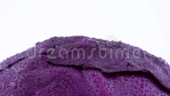 用水滴拍摄一整个迷你紫甘蓝的上部在转盘上慢慢旋转视频的预览图