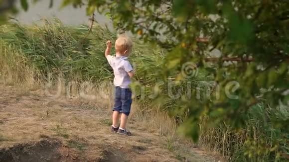 夏天小男孩把一块石头扔进湖里视频的预览图