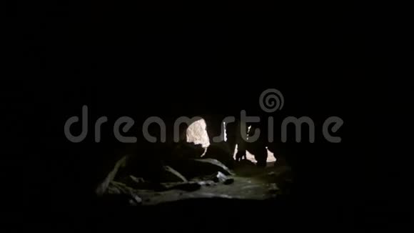 戴着头盔的年轻探险家在黑暗的洞穴里四人乱闯视频的预览图