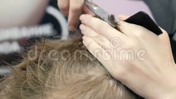理发师用剪刀剪金发短男孩的头发侧视视频的预览图