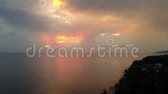 在印度尼西亚巴厘岛通过海滩上的棕榈树从太阳从海面升起的无人机上看到空中景色视频的预览图