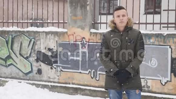 冬天的场景年轻英俊的男子在大雪中摆姿势时间嘴唇视频的预览图
