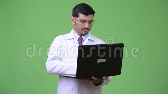 年轻英俊的波斯医生戴着防护眼镜手提电脑视频的预览图