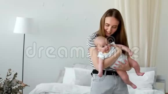 白色公寓中现代年轻家庭的概念妈妈让婴儿上床睡觉给他唱摇篮曲视频的预览图