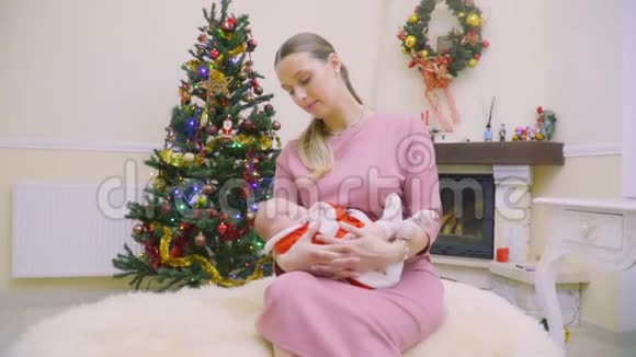 快乐的母亲和熟睡的女儿在圣诞树的背景下视频的预览图