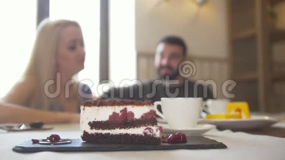 在一对夫妇面前吃着甜蛋糕坐在咖啡馆里享受着交谈视频的预览图