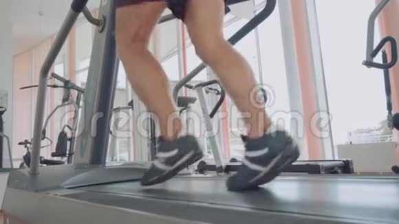 在跑步机上跑步的性感男人靠近脚在健身中心锻炼视频的预览图