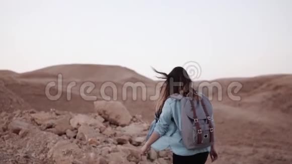女人走在山脚附近慢动作沙漠峡谷边缘的年轻旅游女孩头发在风中飘扬以色列视频的预览图