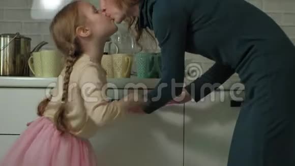 可爱的金发小女孩穿着粉红色的裙子在明亮的厨房里帮助妈妈从洗碗机里拿盘子杯子妈妈视频的预览图
