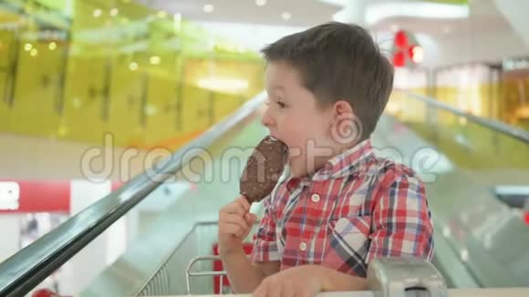 在超市的家庭购物中在购物车里放上美味的冰淇淋可爱的小男孩视频的预览图