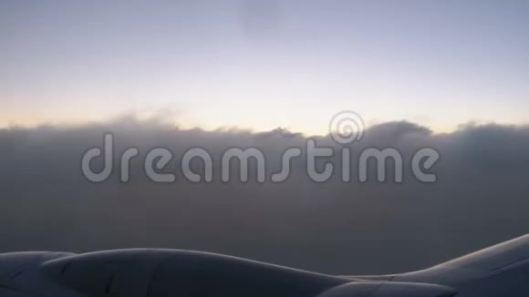 傍晚日落时在云层中飞行的乘客玻璃窗上的景色视频的预览图