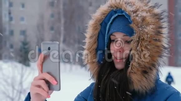 冬天年轻漂亮的女人在手机上视频交谈视频的预览图