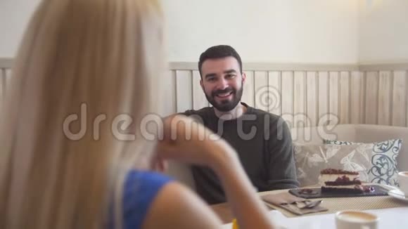 帅气的白种男人在女人面前边聊边享受咖啡厅的谈话视频的预览图