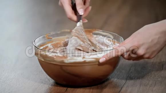 糖果商做面团一只手拿着塑料抹刀在一个用来烤巧克力饼干蛋糕的钢碗里搅拌面团视频的预览图