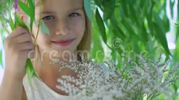一个戴着花冠的金发小女孩在4K的树枝上对着镜头摆姿势视频的预览图