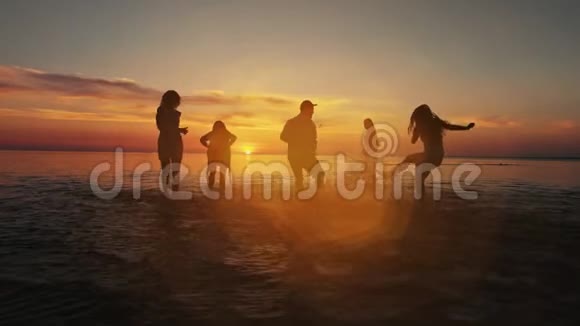 一群快乐的女孩在夕阳下的海滩上在水中奔跑和玩耍美丽快乐的青少年朋友玩得开心视频的预览图