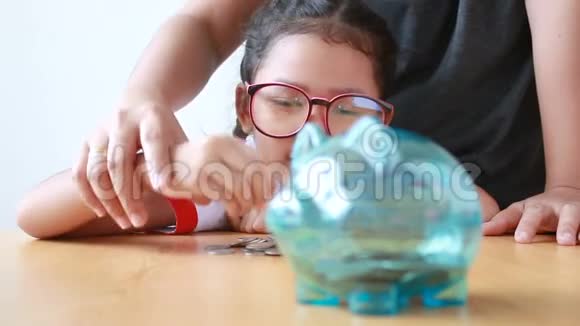 妈妈和亚洲小女孩把钱币放在清储存罐上选择重点放在浅田深处视频的预览图